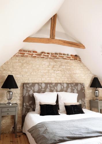 une chambre avec un lit avec un mur de briques dans l'établissement Château de Clermont, à Clermont-les-Fermes