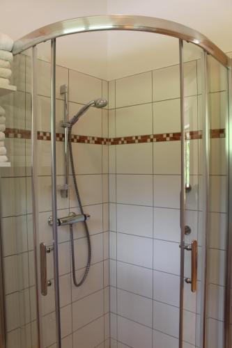 a shower in a bathroom with white tiles at Gartenlodge Auszeit in Nötsch