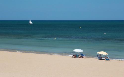 a beach with chairs and umbrellas and the ocean at Denia Playa I in Denia