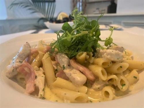 a plate of food with pasta with meat and greens at The Harbour House Sea front Hotel in Portpatrick