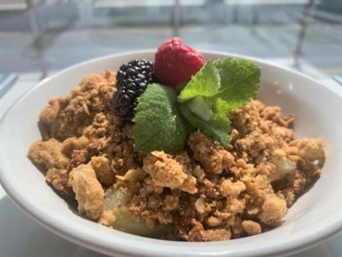 a bowl of food with fruit and mint on a table at The Harbour House Sea front Hotel in Portpatrick