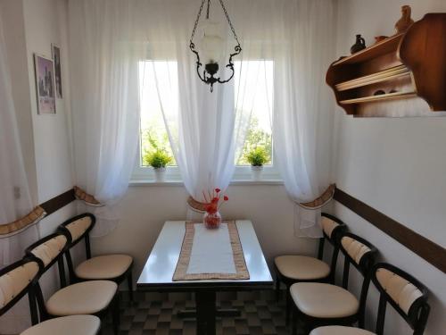 a dining room with a table and chairs and windows at Apartman Maria in Crikvenica