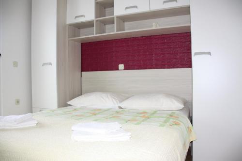 a white bed with white pillows and a red headboard at Guesthouse Santor in Lastovo