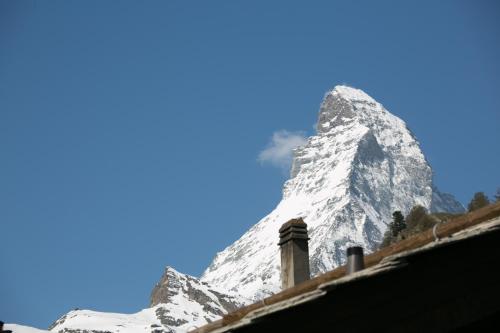 a snow covered mountain in front of a house at Chalet Aroleid Zermatt by Inspiringplaces Zermatt in Zermatt