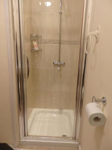 ducha con puerta de cristal y rollo de papel higiénico en HayLaneLodge en Solihull