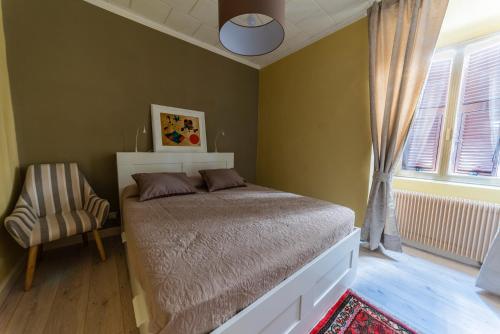 um quarto com uma cama, uma cadeira e uma janela em La casetta colorata em Civitavecchia
