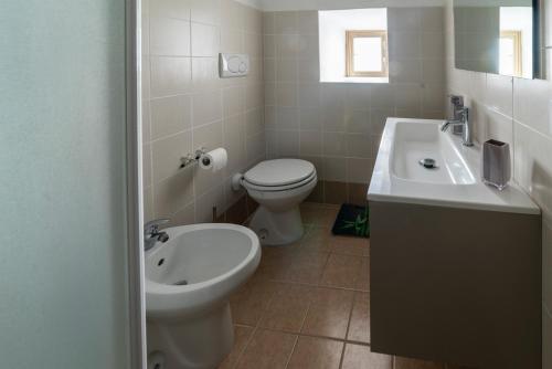 a white bathroom with a toilet and a sink at La casetta colorata in Civitavecchia