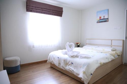 a white bedroom with a bed with a bow on it at TD Bangkok in Bangkok