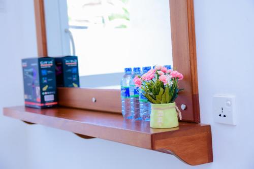 a vase of flowers on a shelf in front of a mirror at Homestay Garden Rest Kandy in Kandy