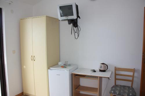 a small kitchen with a refrigerator and a tv on the wall at Guesthouse Santor in Lastovo