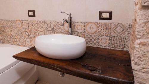 a bathroom with a white bowl sink on a wooden counter at B&b I Trulli dei Desideri in Alberobello