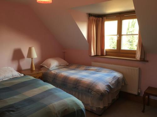 two beds in a room with a window at Jasmine Cottage in Frome