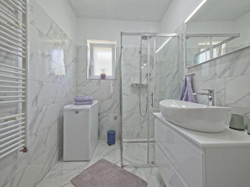 a white bathroom with a sink and a shower at Apartman Nikica in Postira