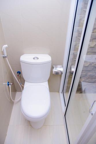 a white toilet in a bathroom with a glass door at Homestay Garden Rest Kandy in Kandy