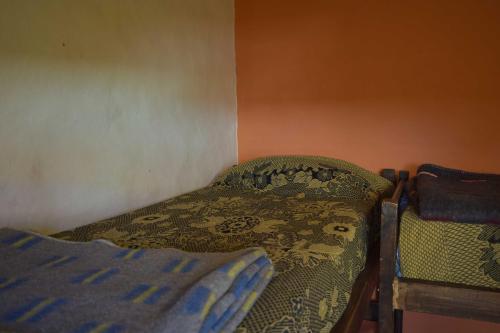 a bedroom with a bed with a blanket and a chair at Tierra Andina Hostel in Tilcara