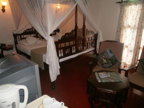 a bedroom with a canopy bed and a chair at Asmini Palace Hotel in Zanzibar City