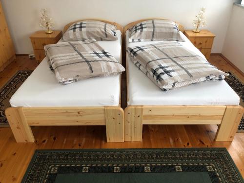 2 camas de madera sobre un suelo de madera en Pacsirta Apartman, en Lenti
