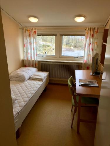 a bedroom with a bed and a desk and a window at STF Malmfältens Folkhögskola in Kiruna