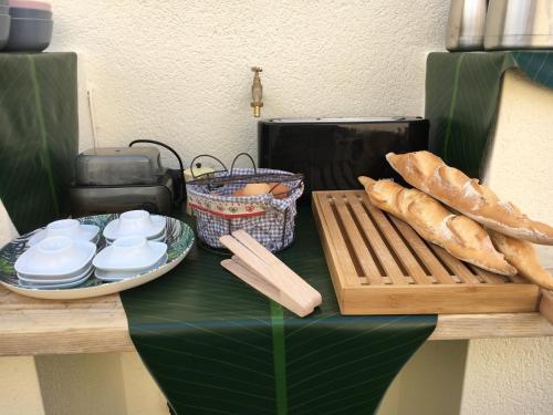 a table with bread and a cutting board and a toaster at Ô 36 Rempart Sud B&B in Aigues-Mortes