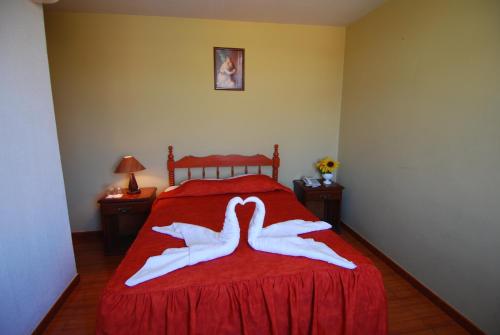 a bedroom with a red bed with two white towels at Hotel Alegria Nasca in Nazca