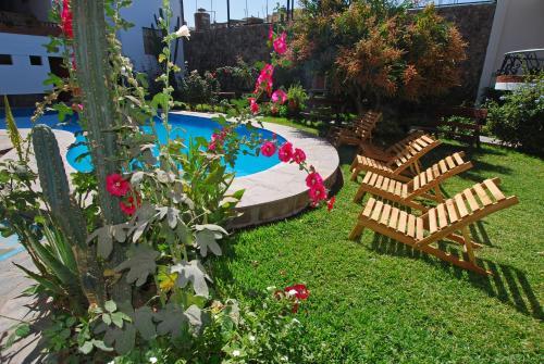 a yard with chairs and a swimming pool with flowers at Hotel Alegria Nasca in Nazca