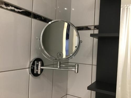 a round mirror on a wall in a bathroom at Apartment 1 mit Terrasse und PKW-Stellplatz in Leverkusen