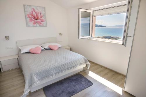 a bedroom with a bed with pink pillows and a window at Apartmani Ticinovic in Omiš