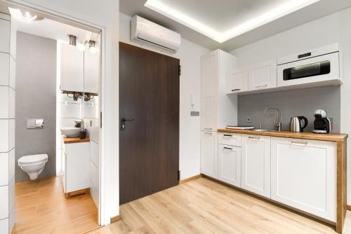 cocina blanca con lavabo y aseo en Toress Apartamenty Deptak, en Szczecin