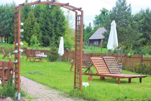 a wooden arch with a bench in a yard at Cichosza - The Sound Of Silence in Białowieża