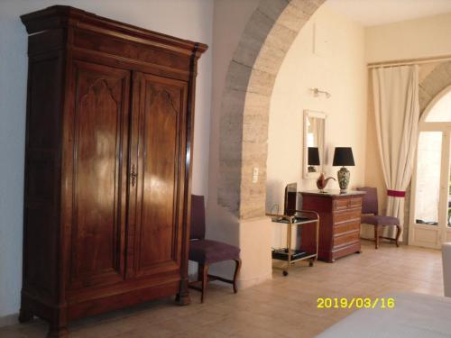 a room with a large wooden cabinet and a bedroom at LA CHAPELLE DU PRIEURE in Alignan-du-Vent