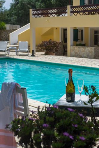 a bottle of wine and two glasses next to a swimming pool at Villa Elaia Suites & Apartments No.1 in Gaios
