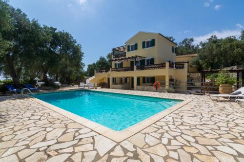 a villa with a swimming pool in front of a house at Villa Elaia Suites & Apartments No.1 in Gaios