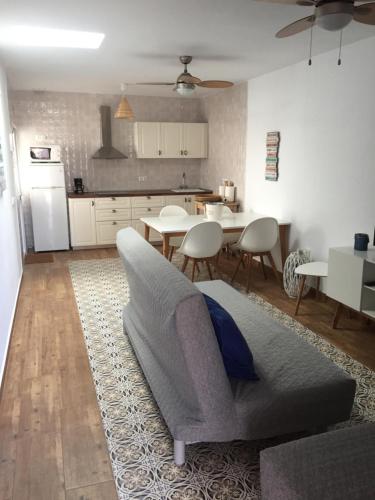 a living room with a gray couch and a kitchen at Chalet adosado playa de La Barrosa in Chiclana de la Frontera