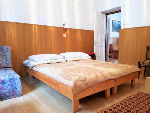 a bed in a room with a wooden wall at Muskátli Üdülőház in Parádfürdő-Peres