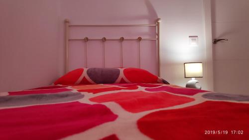 1 dormitorio con 1 cama roja y blanca con lámpara en Loft 500 metros de la playa, en Cádiz