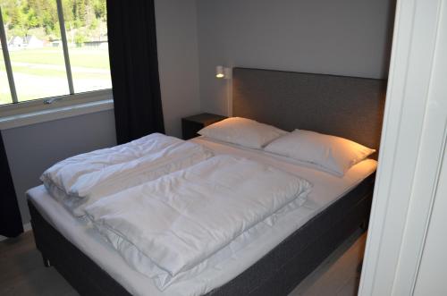 een bed met witte lakens en kussens in een slaapkamer bij Einemo Apartments in Lærdalsøyri