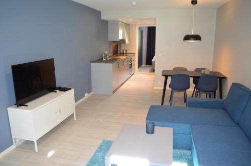 a living room with a blue couch and a kitchen at Einemo Apartments in Lærdalsøyri