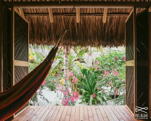 a hammock in a room with flowers and plants at Dos Aguas Lodge in Rincón