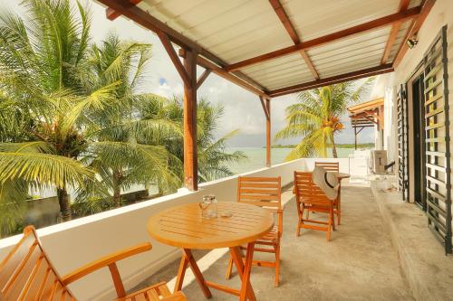 a porch with a wooden table and chairs and the ocean at Auberge SeaFever in Mahébourg