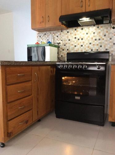 a kitchen with a black stove and wooden cabinets at Oasis Palma Real santiago, Republica Dominicana in Santiago de los Caballeros