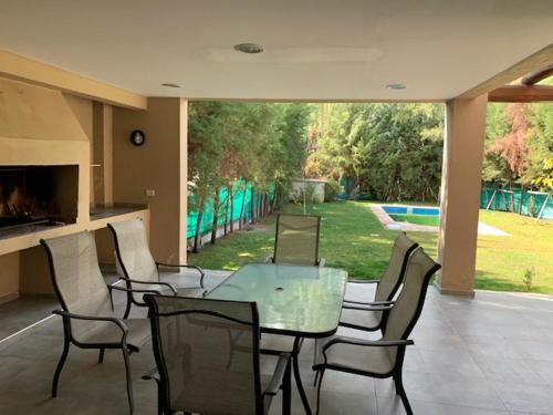 een eetkamer met een glazen tafel en stoelen bij Mendoza Casa Barrio Cerrado in Chacras de Coria