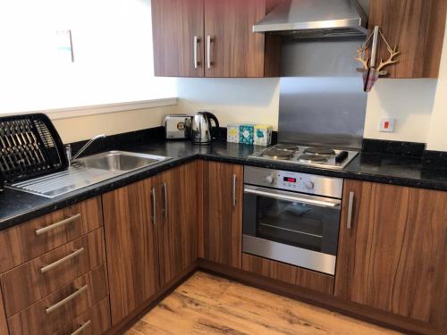 a kitchen with wooden cabinets and a sink and a stove at 41 Larchwood Drive Holiday Home in Inverness