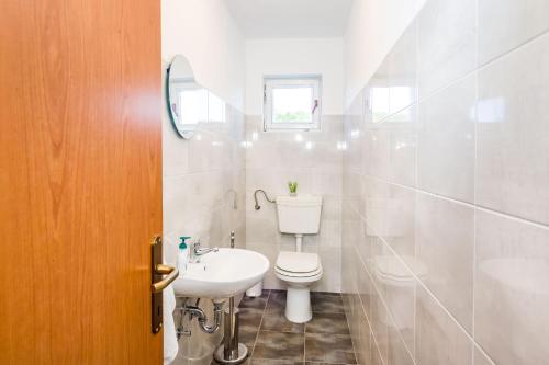 a white bathroom with a toilet and a sink at Holiday home Ante with beautiful private garden in Nadin