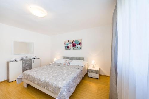 a white bedroom with a bed and a tv at Holiday home Ante with beautiful private garden in Nadin