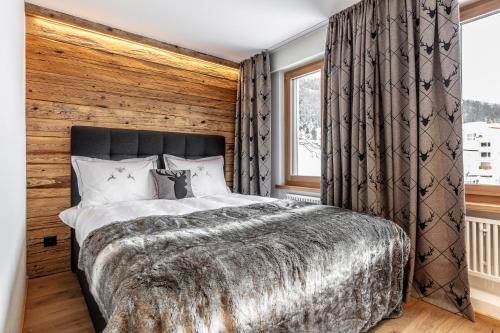 1 dormitorio con 1 cama grande y pared de madera en Unique Alpic style apartment in the heart of Davos en Davos