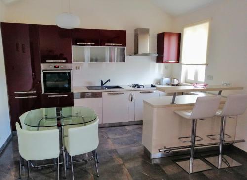 a kitchen with a glass table and white chairs at Apartment Markorcula in Korčula