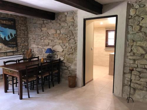 a dining room with a wooden table and a stone wall at Weekend en Provence in Comps