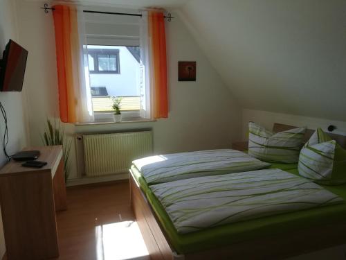 a bedroom with a bed and a window with orange curtains at Ferienwohnung Düne in Ostseebad Sellin