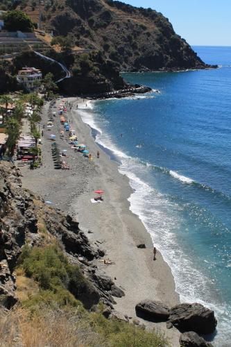 a beach with a bunch of people and the ocean at Dúplex playa Cabria in Almuñécar