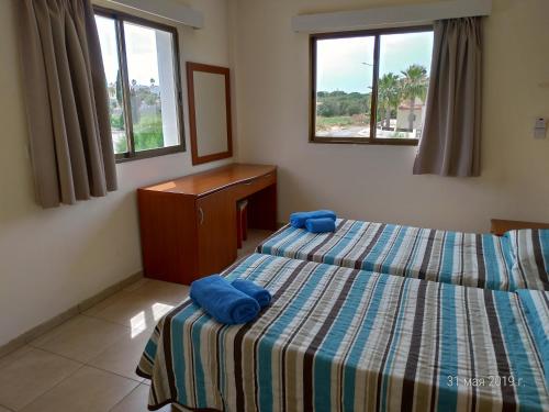 sypialnia z 2 łóżkami i komodą oraz 2 oknami w obiekcie Maricosta Apartments w mieście Protaras